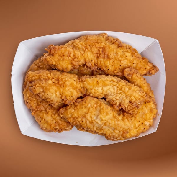 Crispy golden-brown chicken tenders in a white paper tray against a brown background.